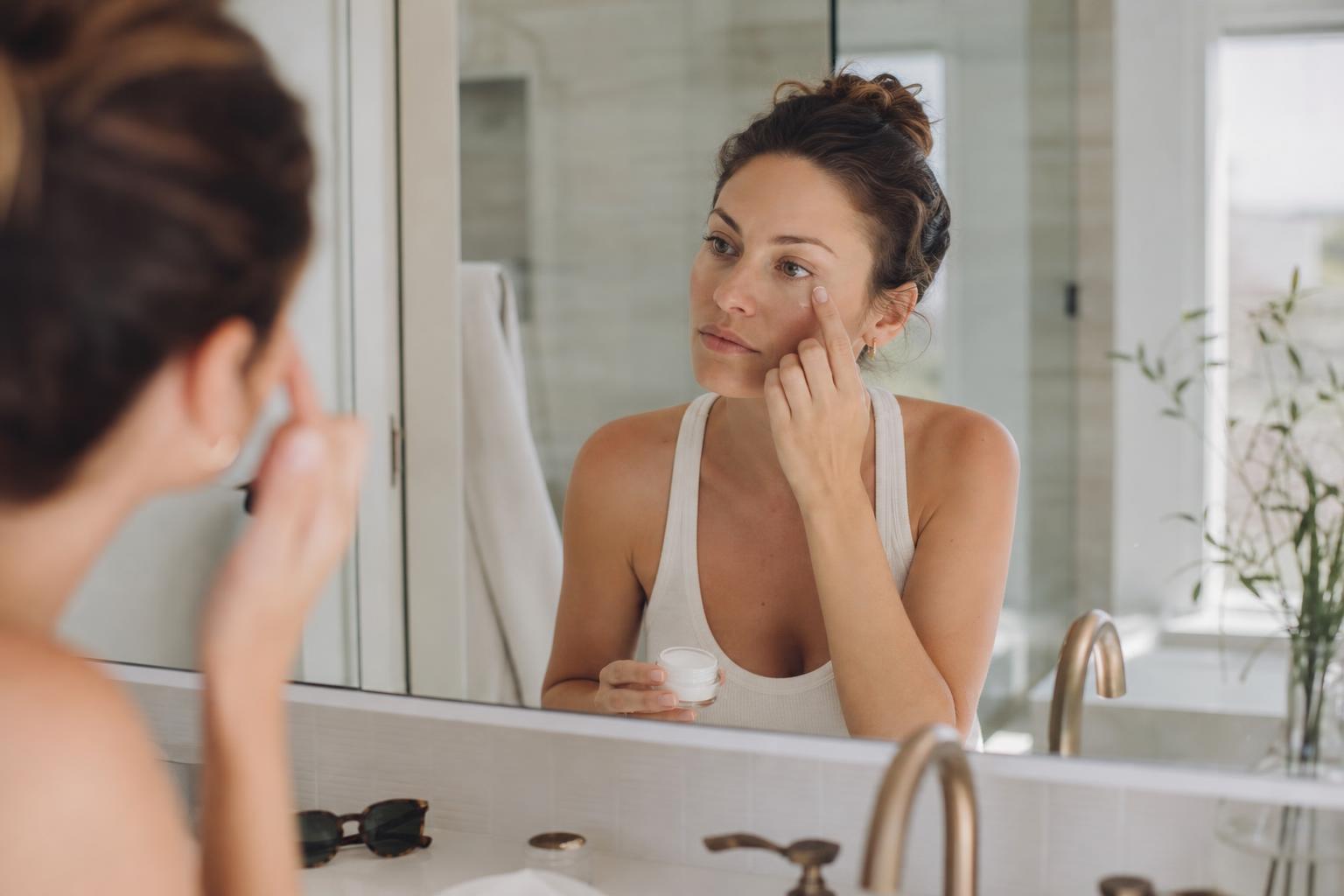 Woman gently applying moisturizer around her eye area