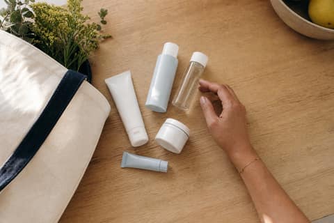 Overhead view of simple skincare products on a kitchen counter beside a canvas tote bag